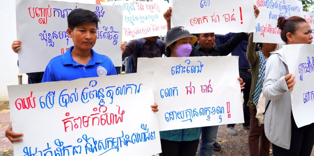 Workers with signs in Khmer at Wing Star Shoes